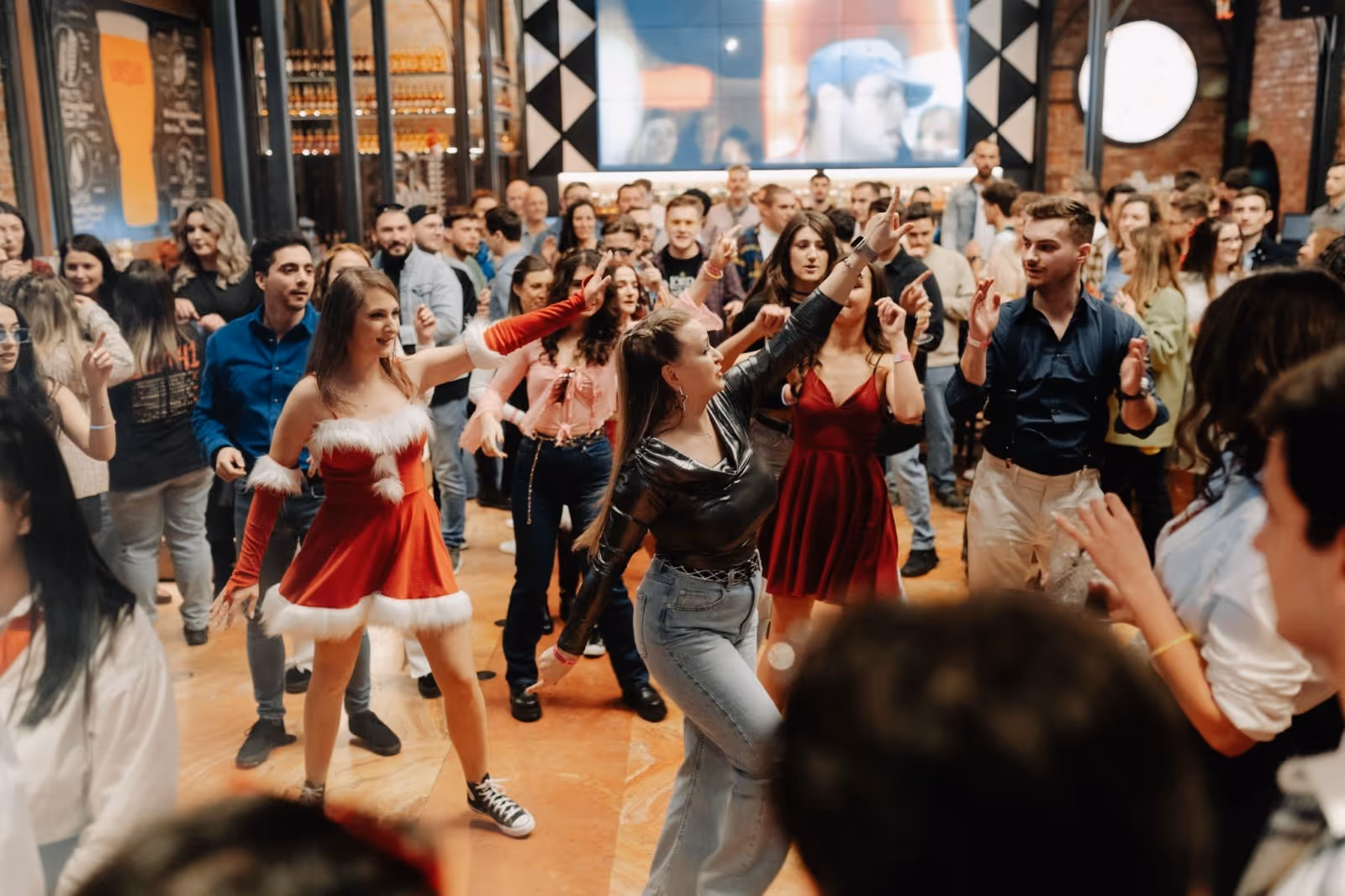 A group of people dancing in a room with a crowdDescription automatically generated
