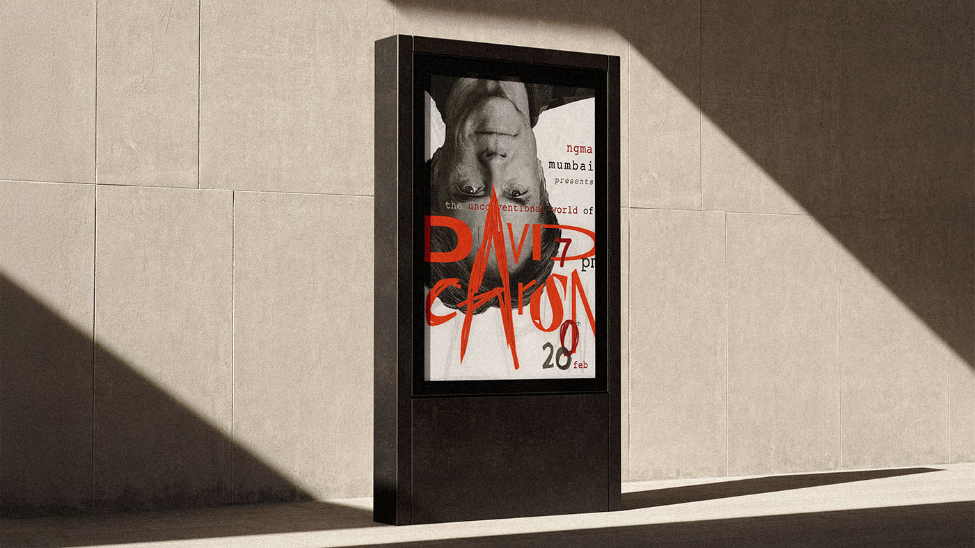 Outdoor digital display on a beige wall showing an upside-down black and white poster design of david Carson with red text announcing an event featuring David Carson on February 20 at 7 pm.