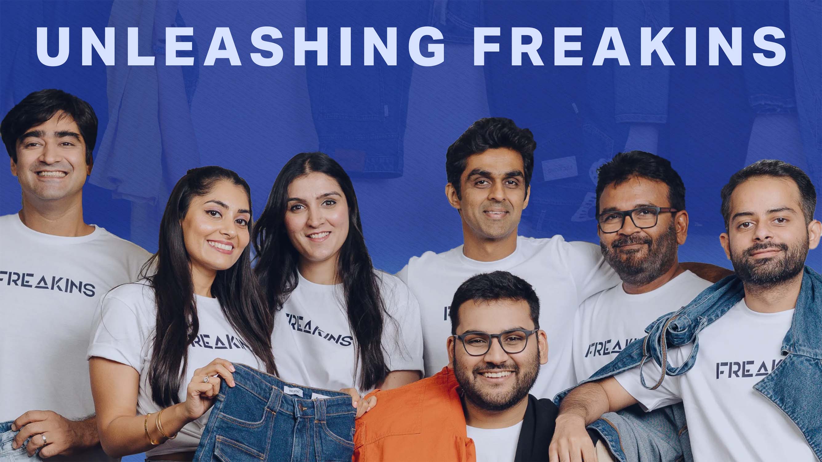 Freakins team of seven smiling adults wearing Freakins branded t-shirts in front of a blue background with the text 'UNLEASHING FREAKINS'.