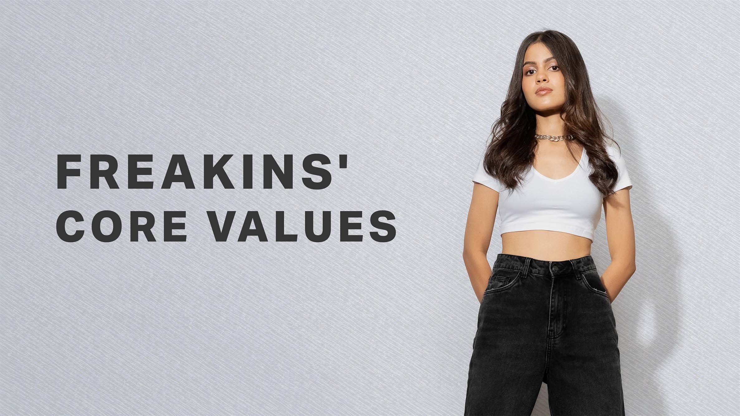 Young woman in black jeans and white crop top standing with hands in pockets next to text reading 'Freakins' Core Values' on a light textured background.