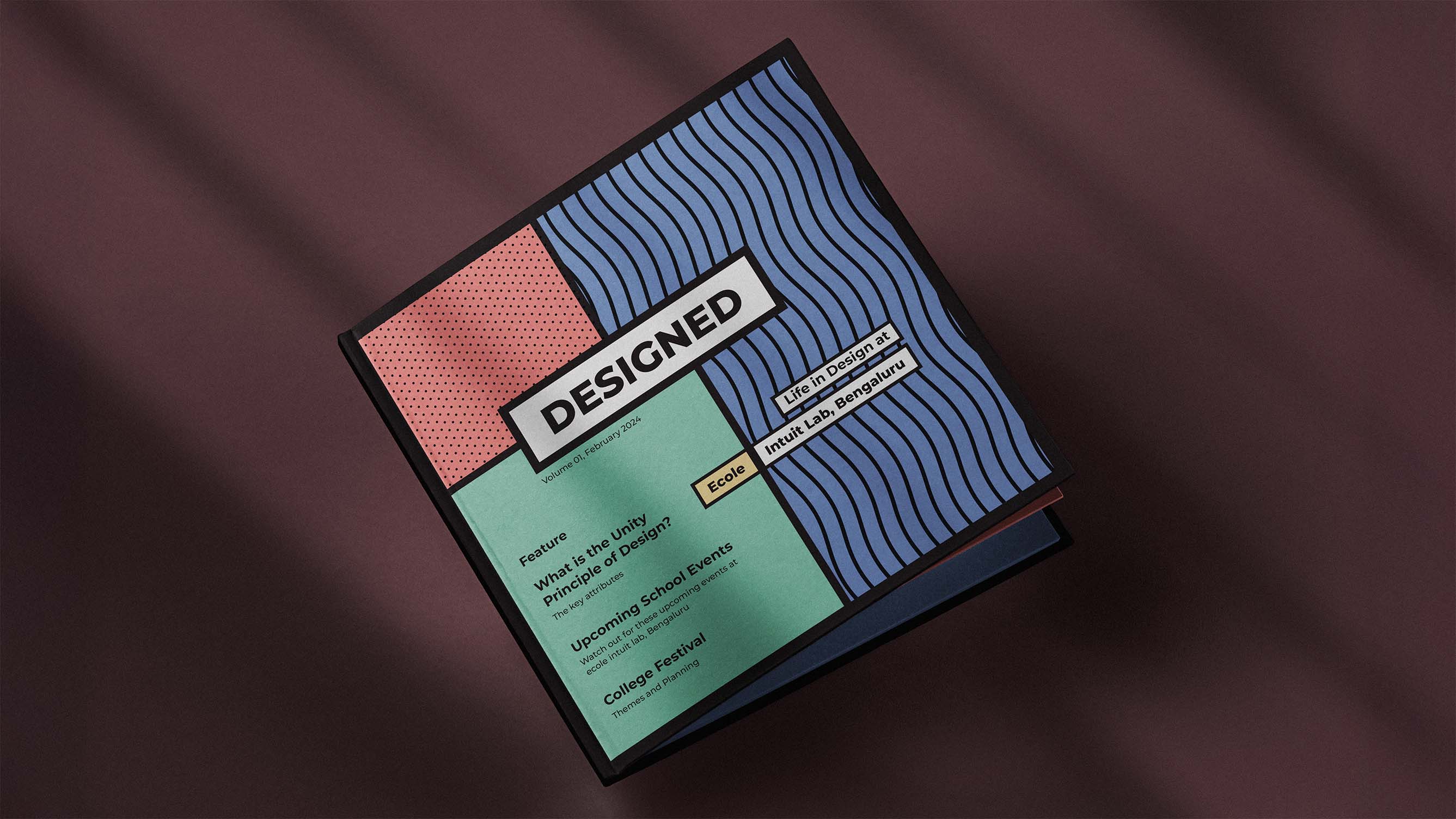 Square-shaped Magazine titled 'DESIGNED' with colorful geometric cover featuring text about design principles, school events, and college festival, placed on a dark surface with shadows.