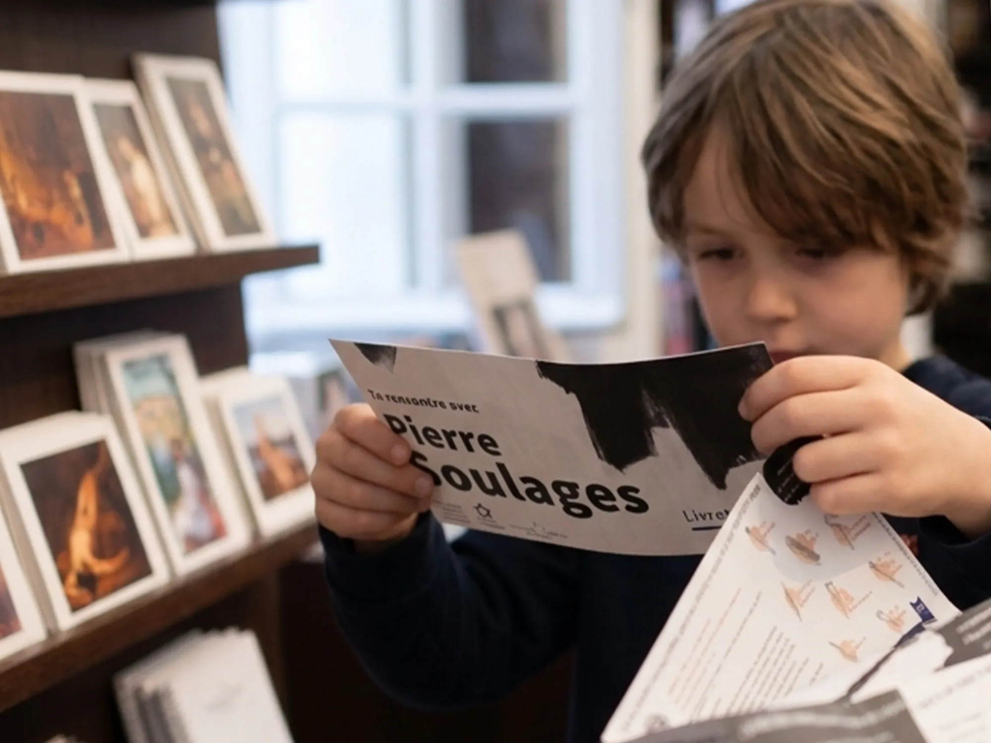 Un enfant ouvre le livret jeux dans la libraire du Musée.