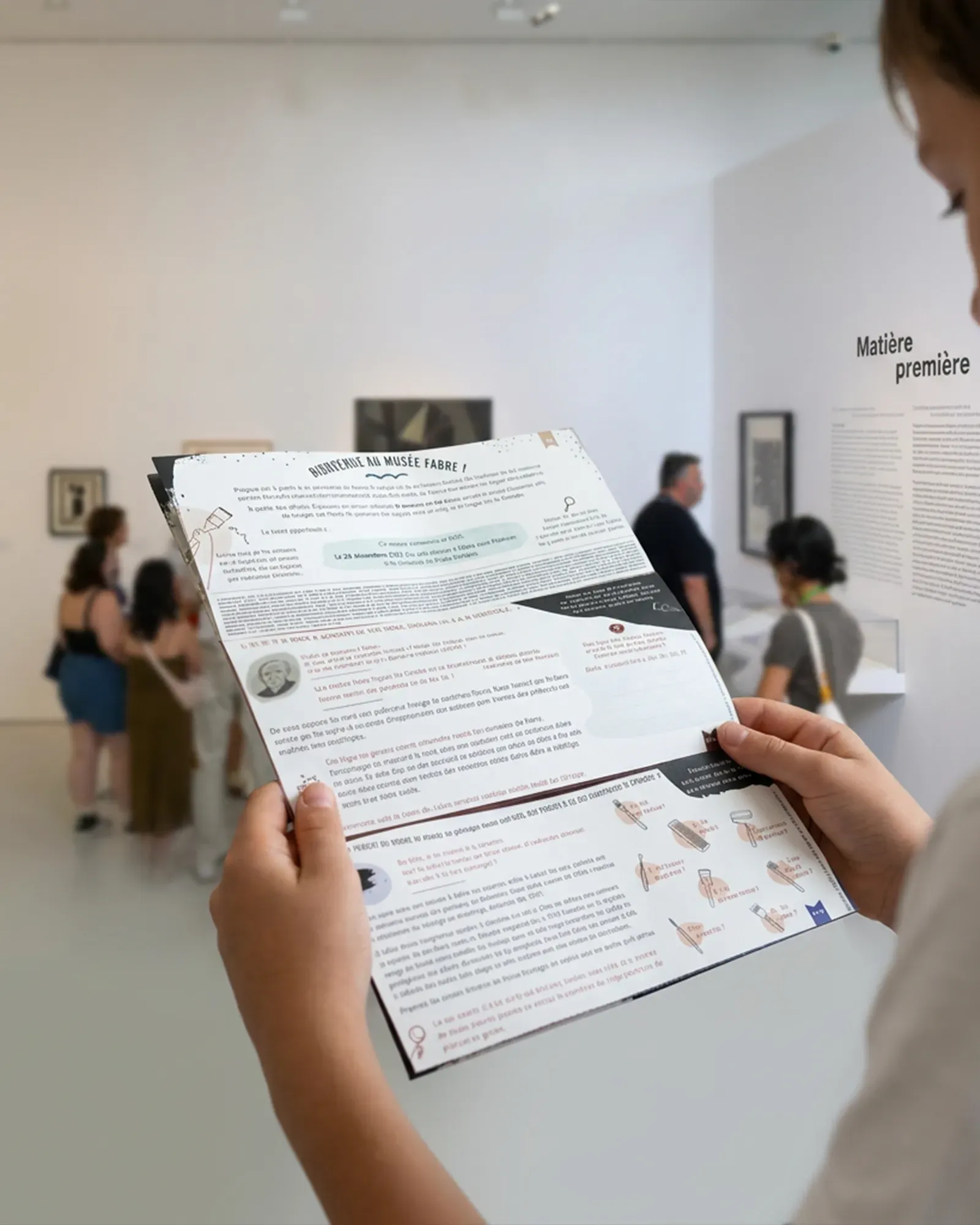 un jeune garçon a le livret jeux sous les yeux dans une salle de l'exposition.