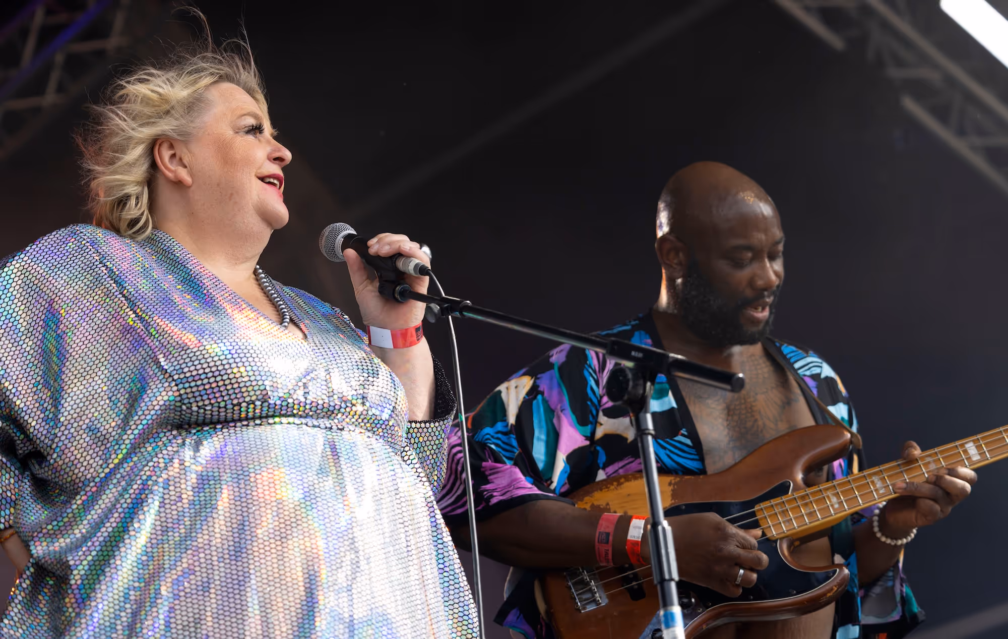 A woman singing with a man on the bass next to her