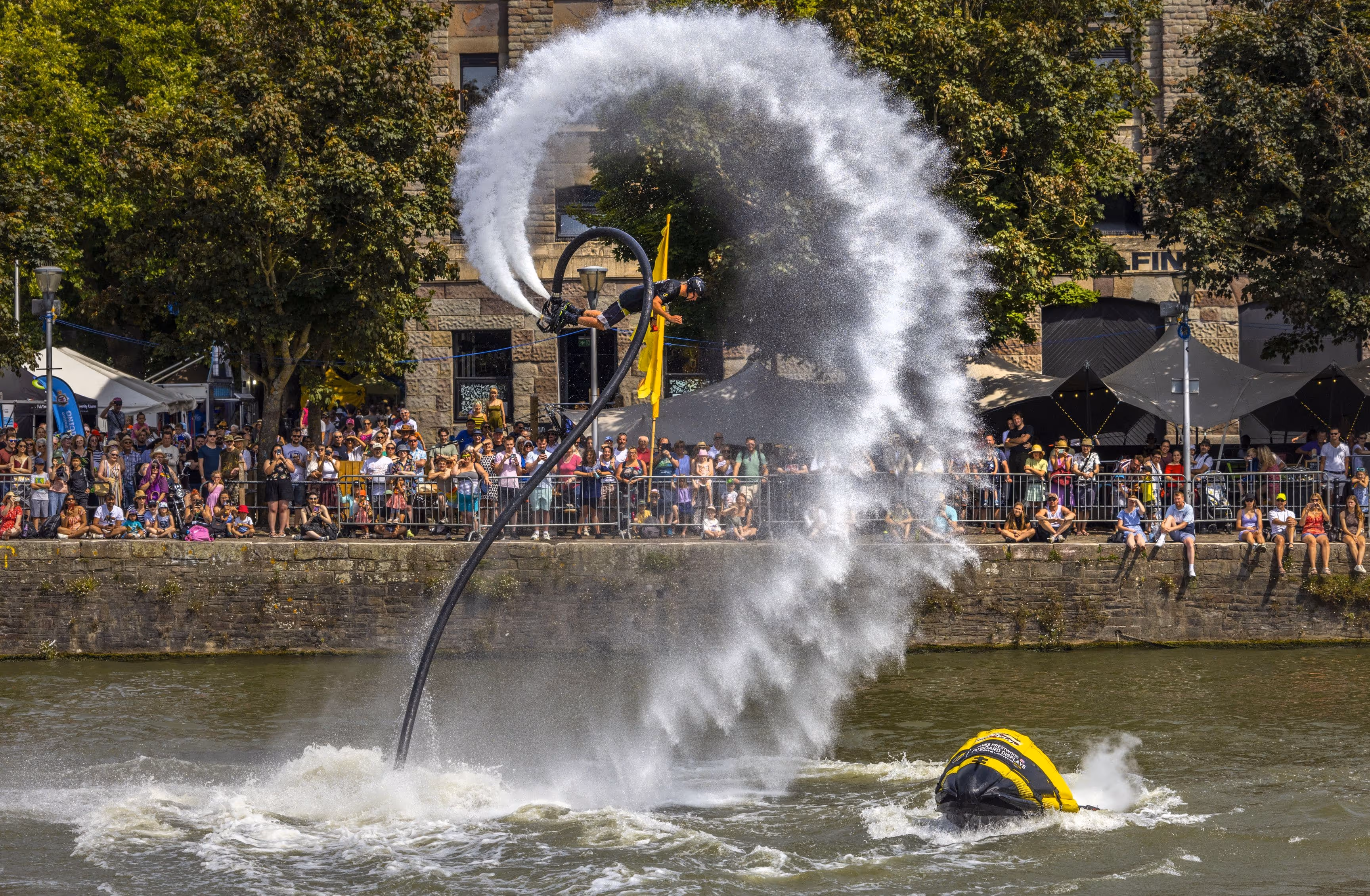 Man with water jets on foot doing a back flip