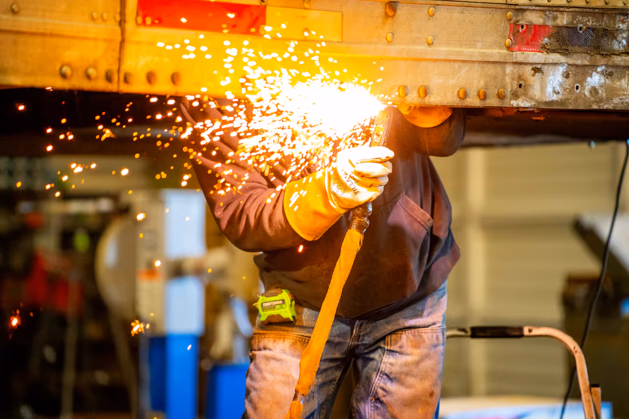mechanic welding a truck frame in a shop bay 