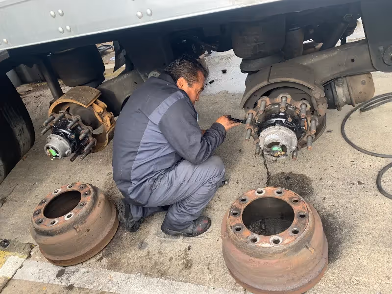 Brake drum service on a heavy-duty trailer as a technician inspects wheel hub components with drums removed.