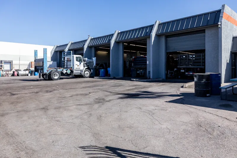 Heavy-duty truck repair facility with open service bays and a commercial truck parked outside for maintenance.