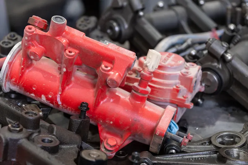 Heavy-duty repair with a red engine component removed for service, surrounded by valvetrain parts during engine rebuild.