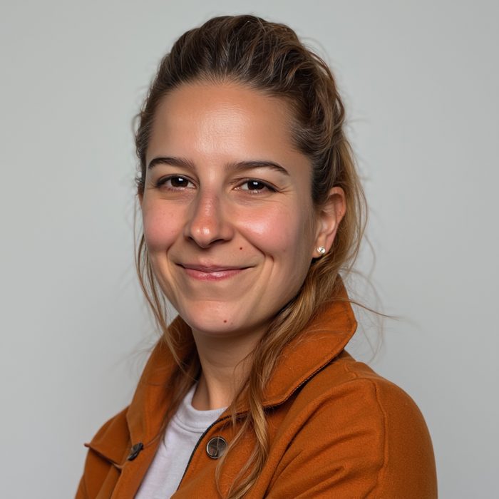 Portrait of Valentina Vicent, smiling, in a rust-orange jacket
