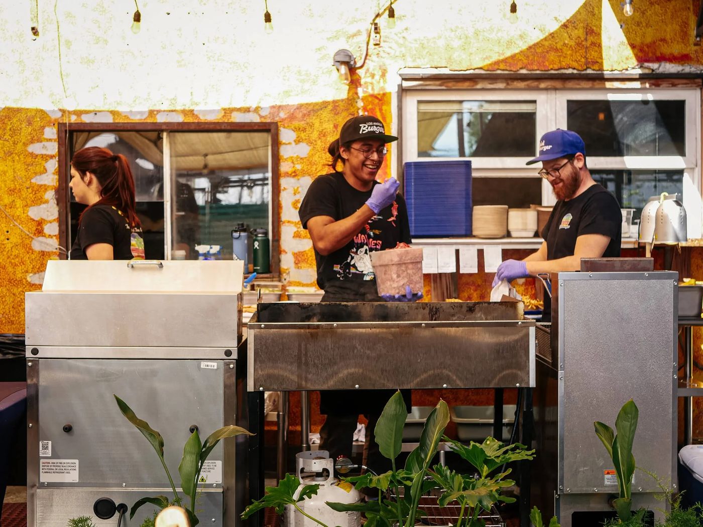 The Goldburger crew working the flat-top grill under string lights, smiling