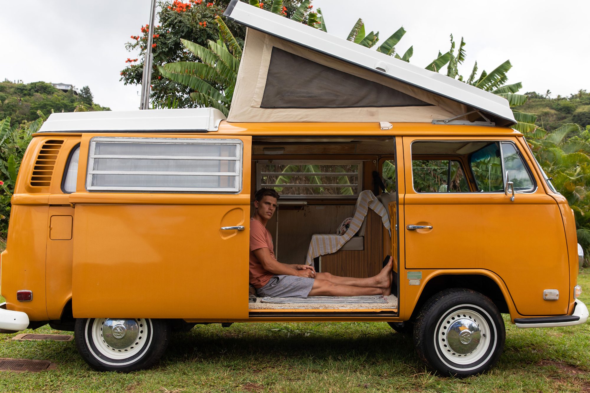 An orange camper van parked under palm trees