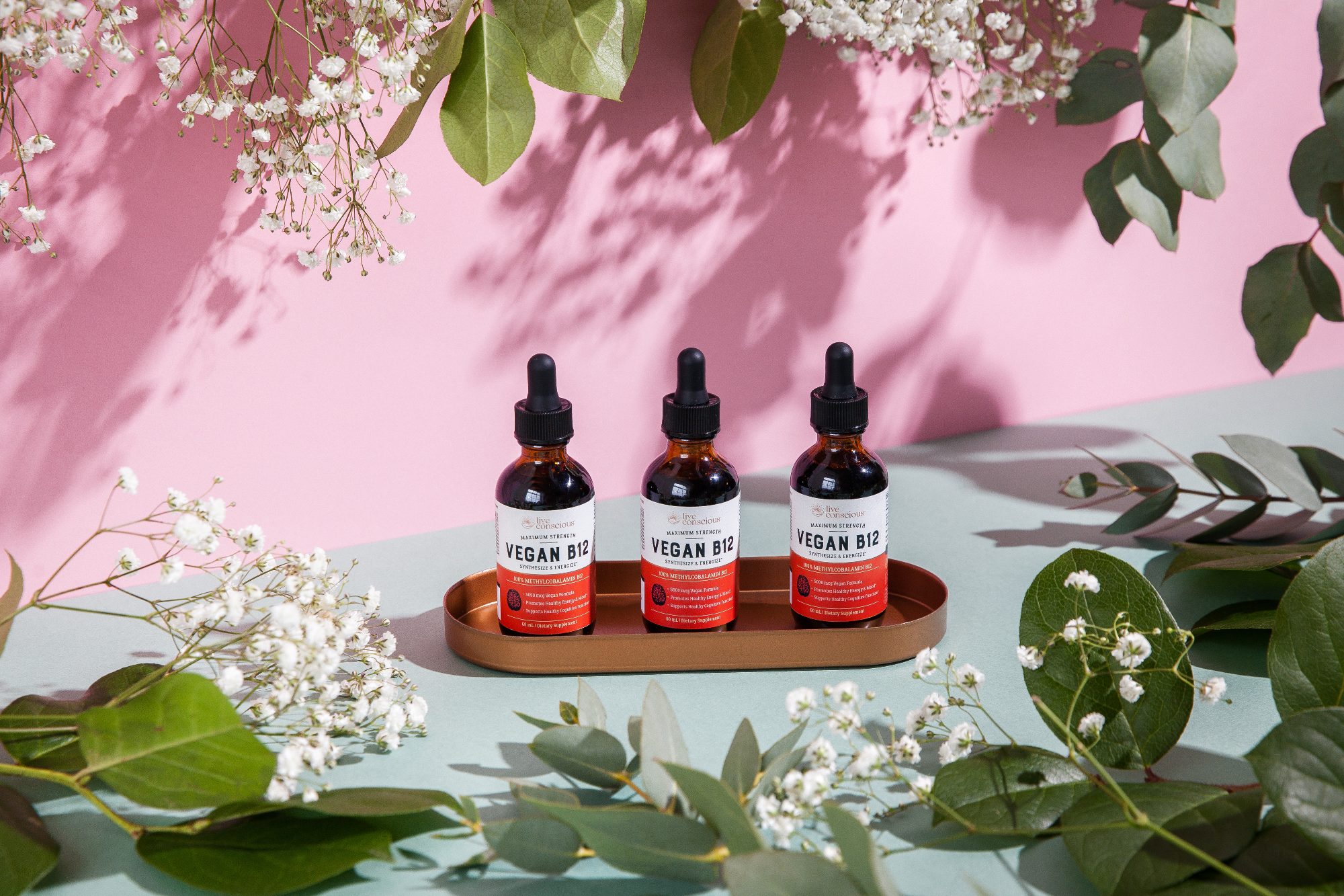 Vegan B12 dropper bottles among white flowers