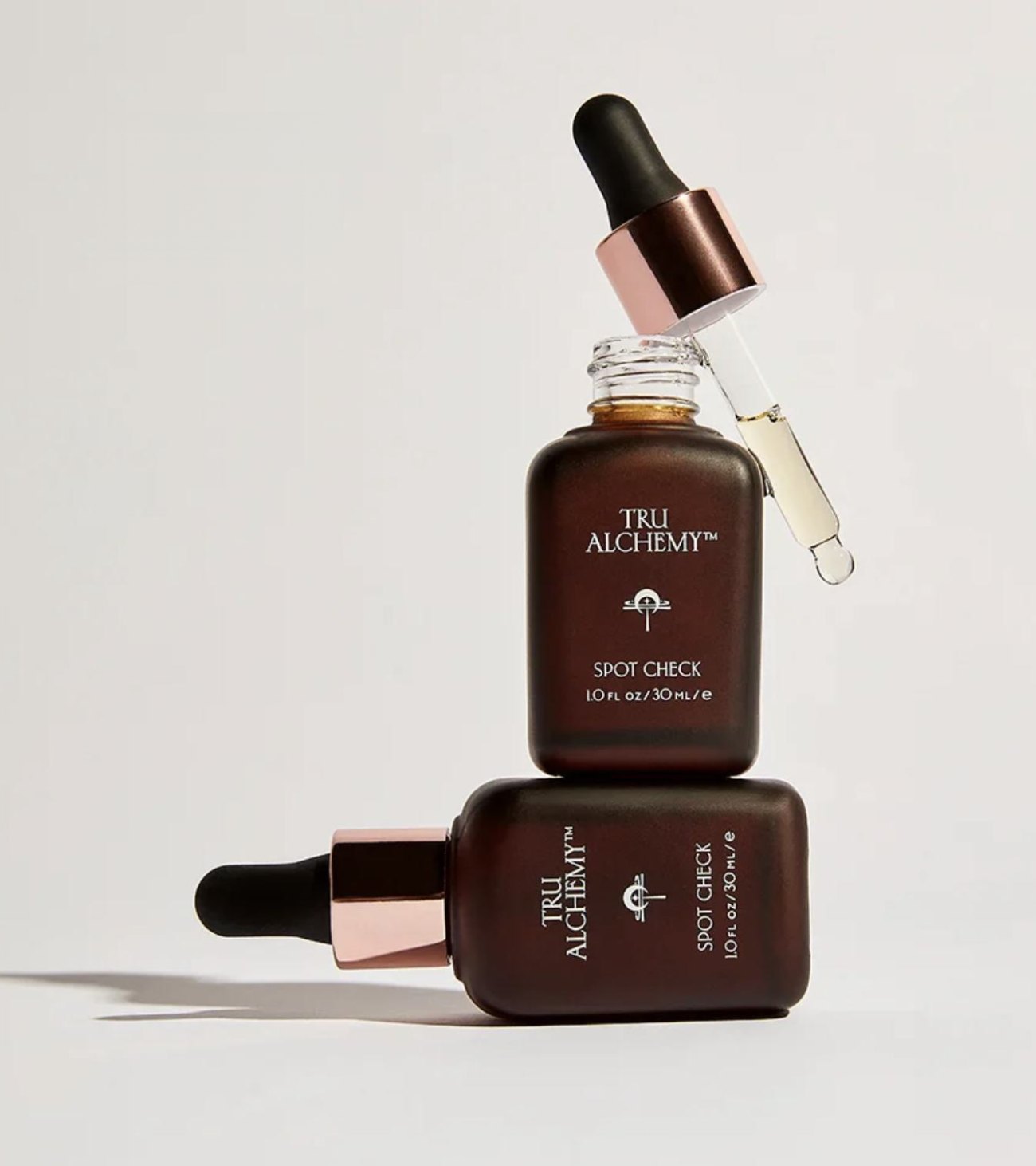 Two Tru Alchemy Spot Check dropper bottles with rose gold caps