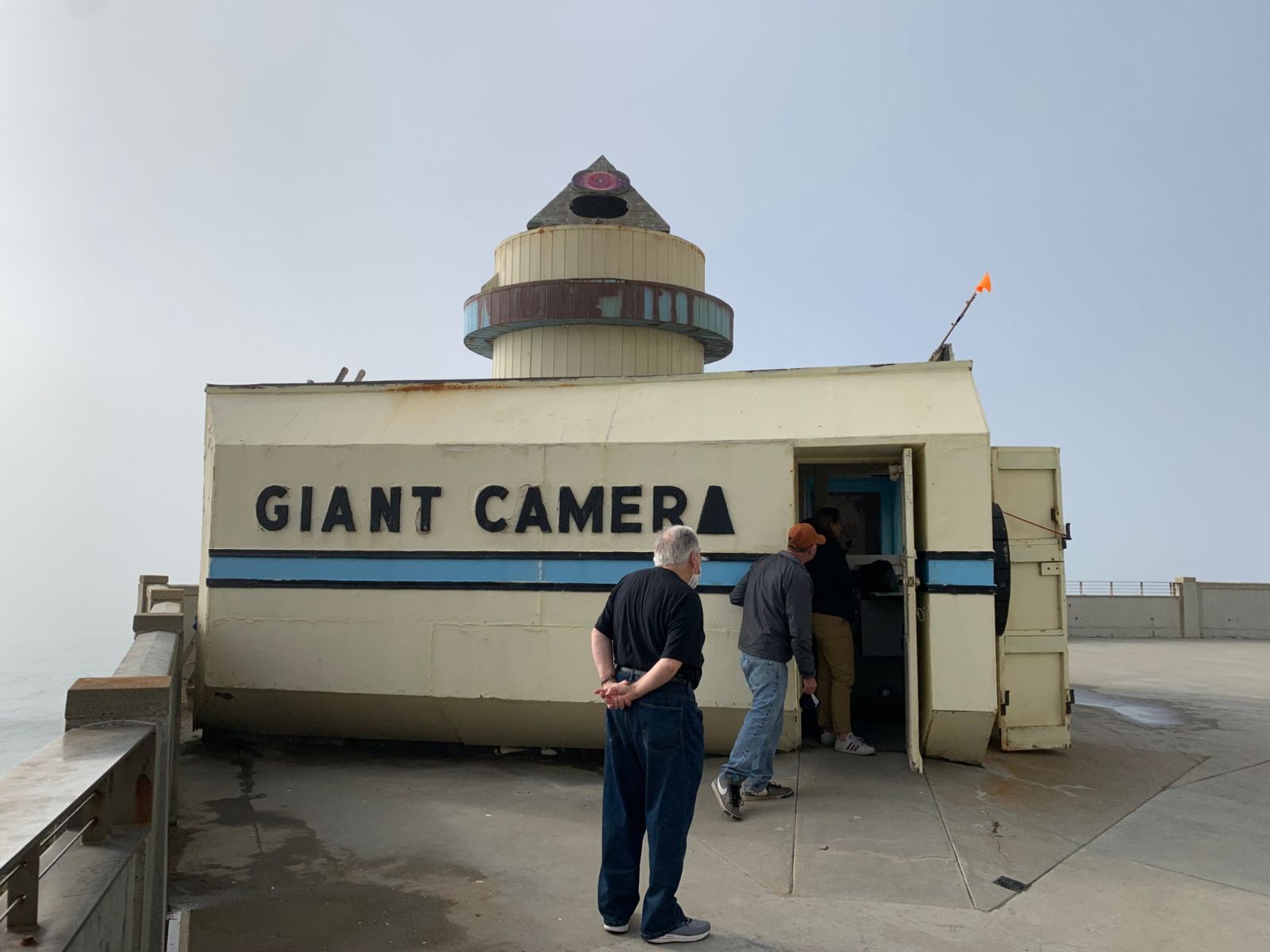 The Giant Camera building at Point Lobos, a small white building shaped like a box camera, with visitors at its door