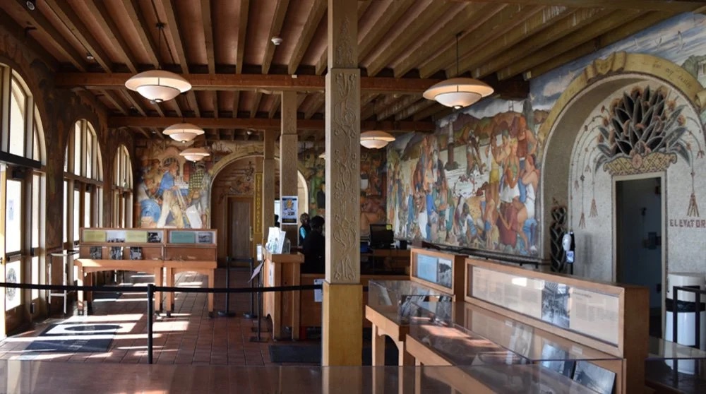 The lobby of the Beach Chalet, with a wood-beamed ceiling and Depression-era frescoes along the walls