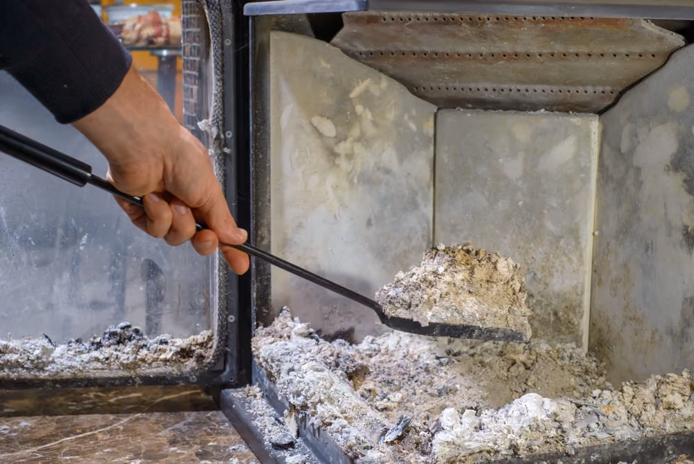 A close-up view of dangerous creosote buildup being carefully removed from a brick fireplace during a professional chimney sweep service in Mt. Shasta.