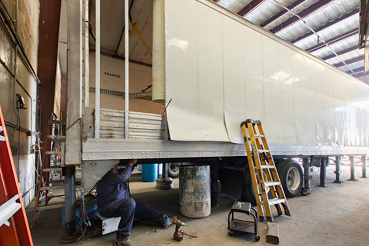 Professional maintenance on a box trailer as a technician repairs the underside in a Southern California fleet service shop.