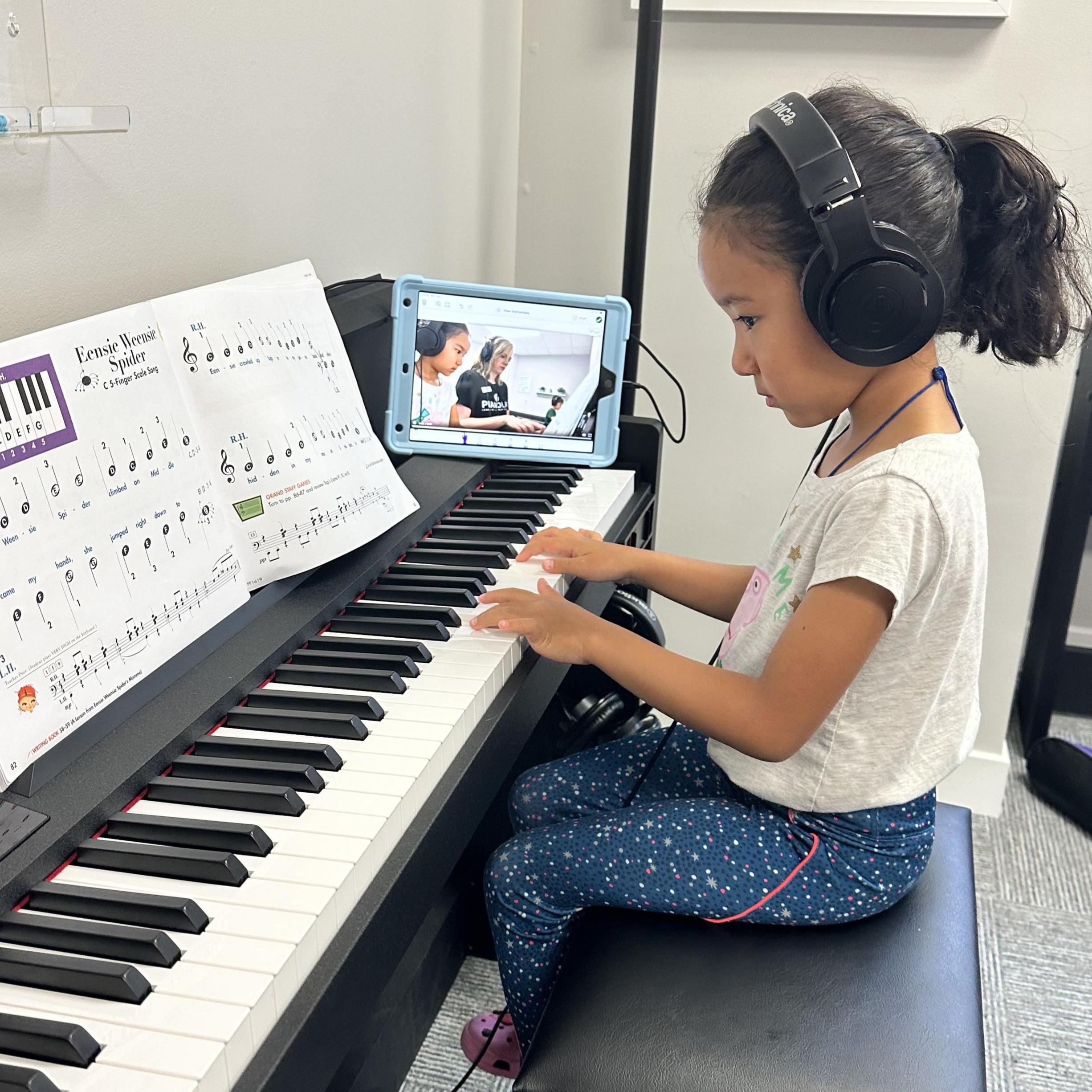 A young student playing piano with an iPad in the background