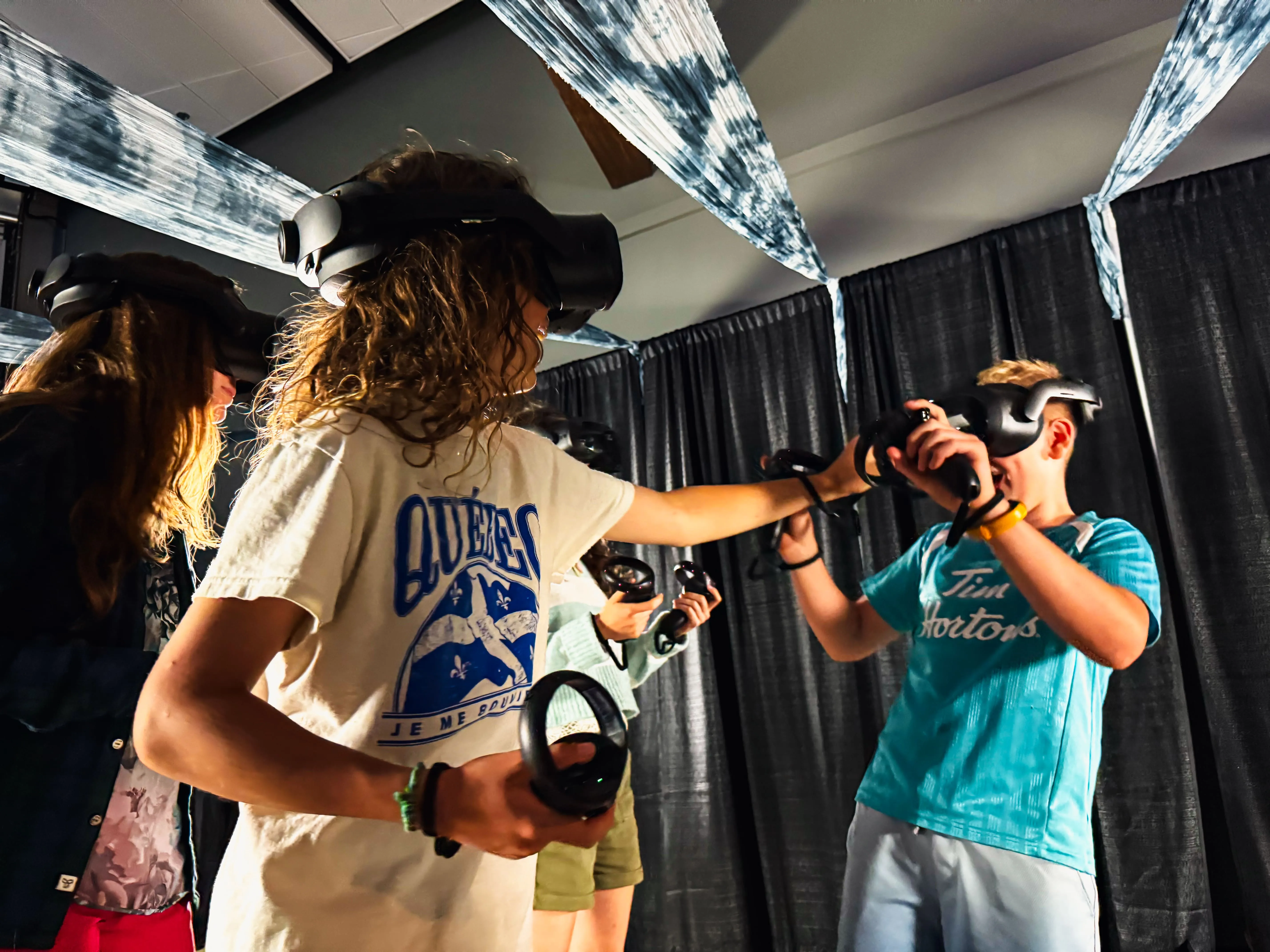 Young guests in VR headsets reach out toward objects only visible inside the experience.