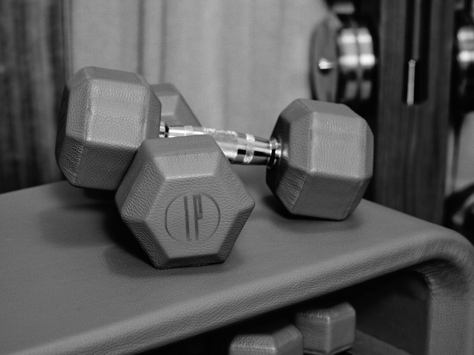 Un par de mancuernas hexagonales colocadas sobre un banco de musculación en un gimnasio.