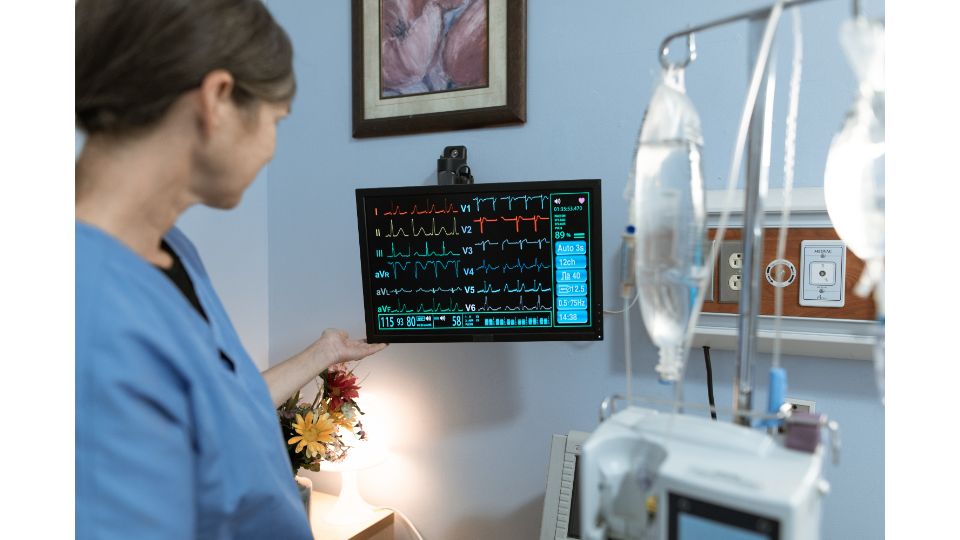 Pflegekraft überwacht Patientenmonitor auf einer Intensivstation während der Weiterbildung in Intensivpflege und Anästhesie.