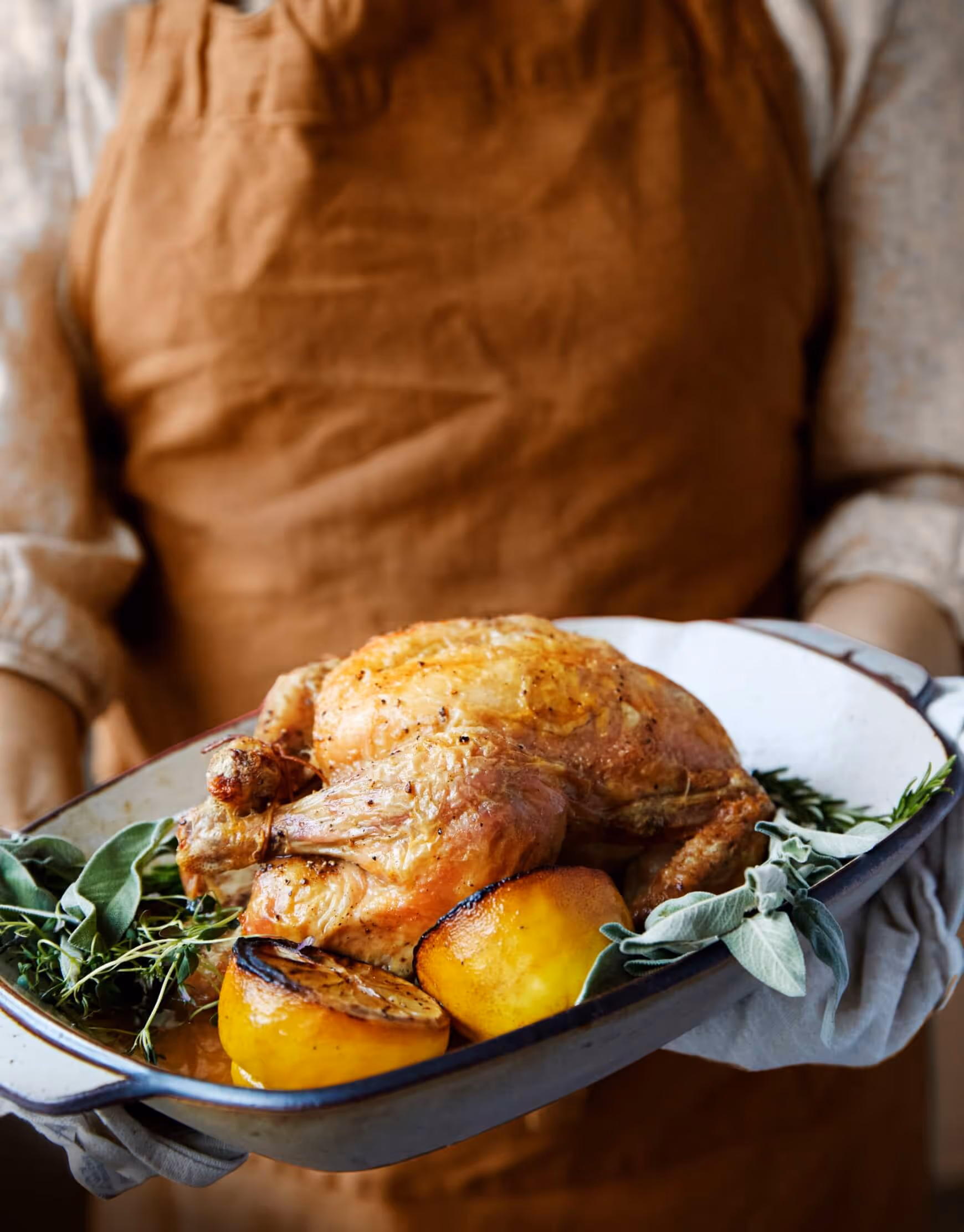 A chef holding a plate with a cooked chicken