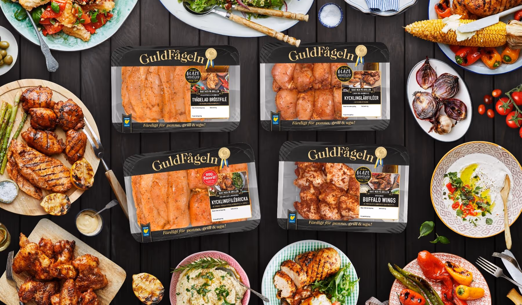 Four packages with raw chicken from Guldfågeln surrounded with many dishes with chicken.