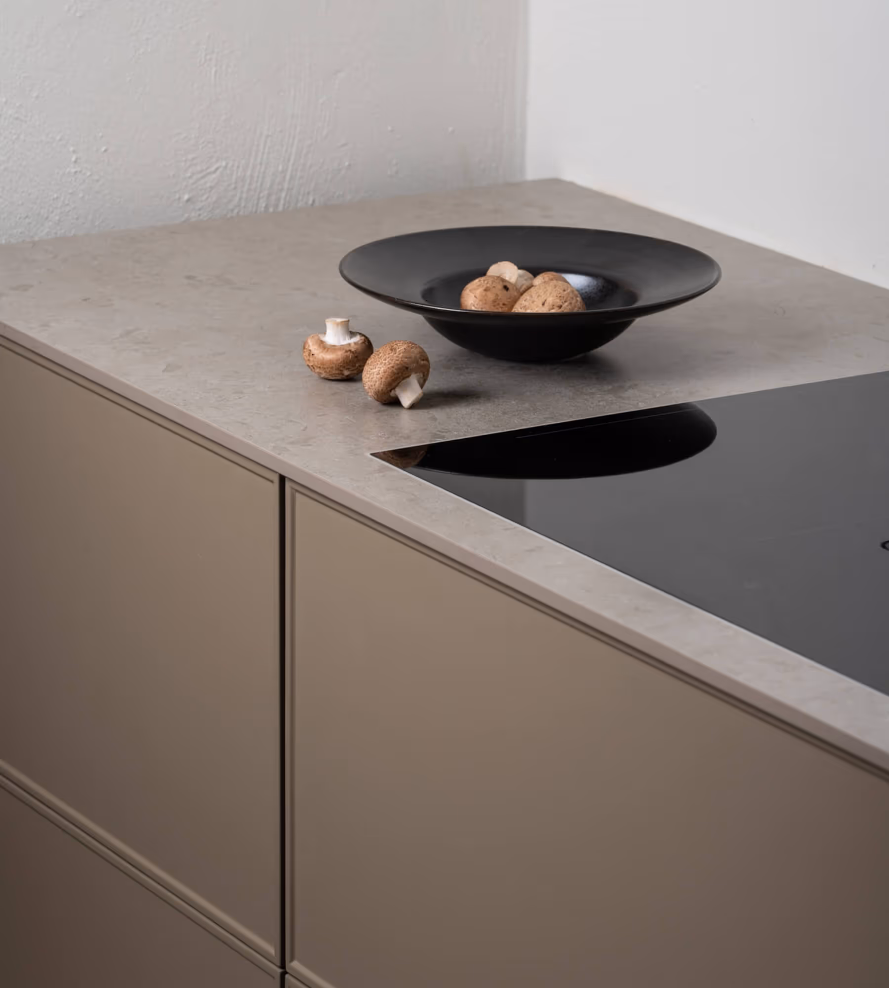 A photo of a stove with a bowl of mushrooms on the side