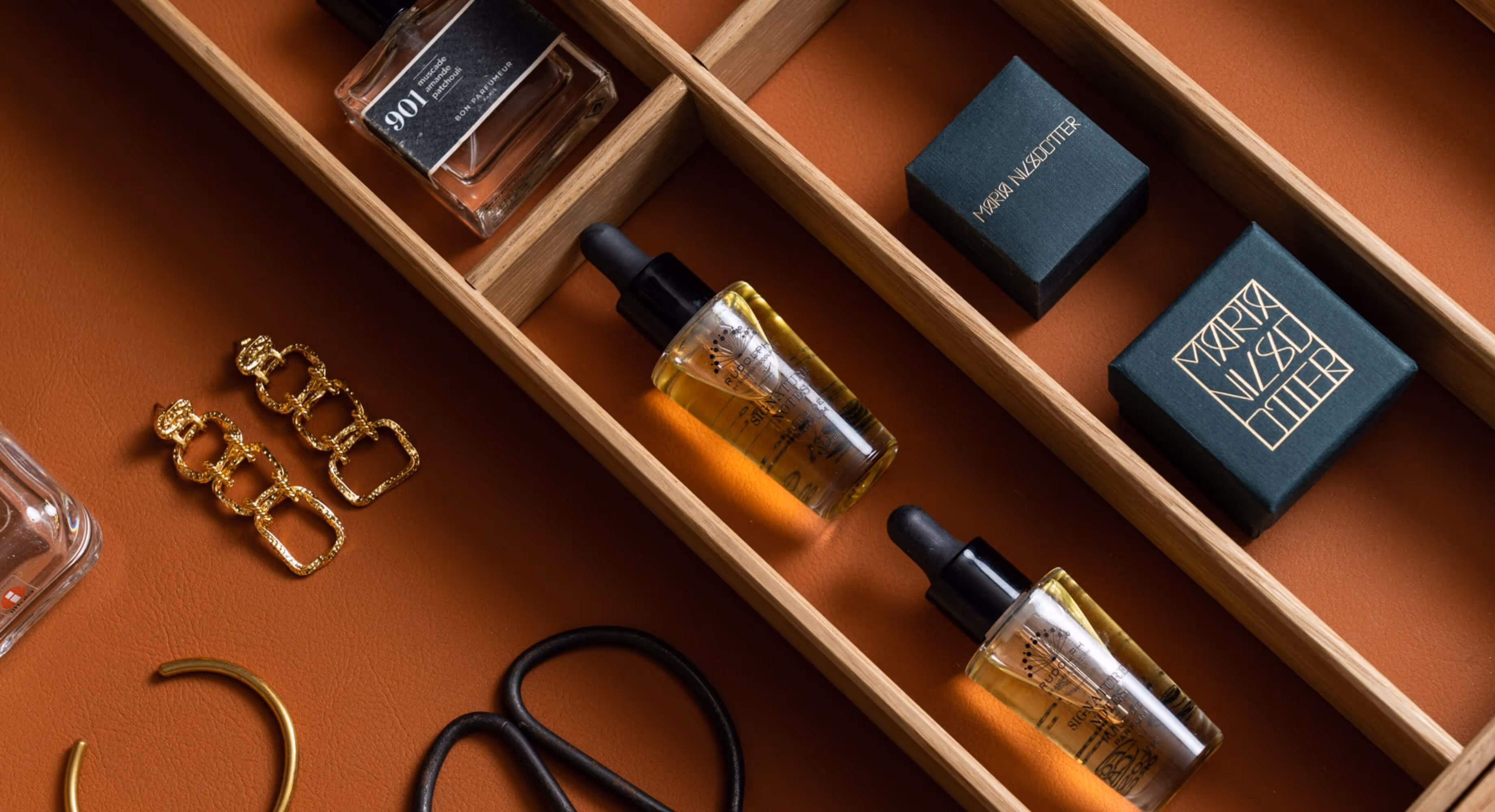 An open drawer with perfumes and jewelry.