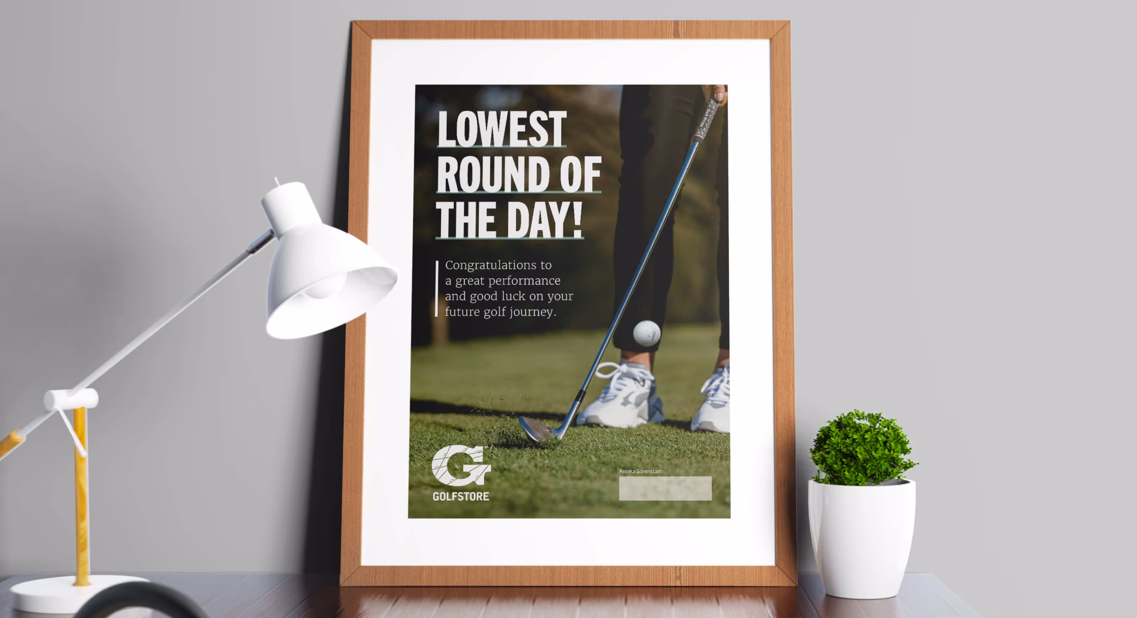 A photo of a shelf with a framed ad from Golfstore with the text "Lowest round of the day!"