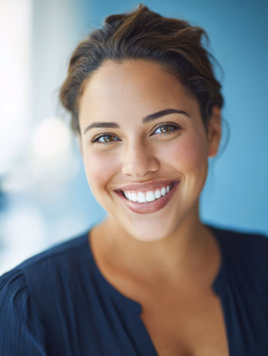 Jeune femme souriante aux cheveux bruns avec un fond bleu flou.