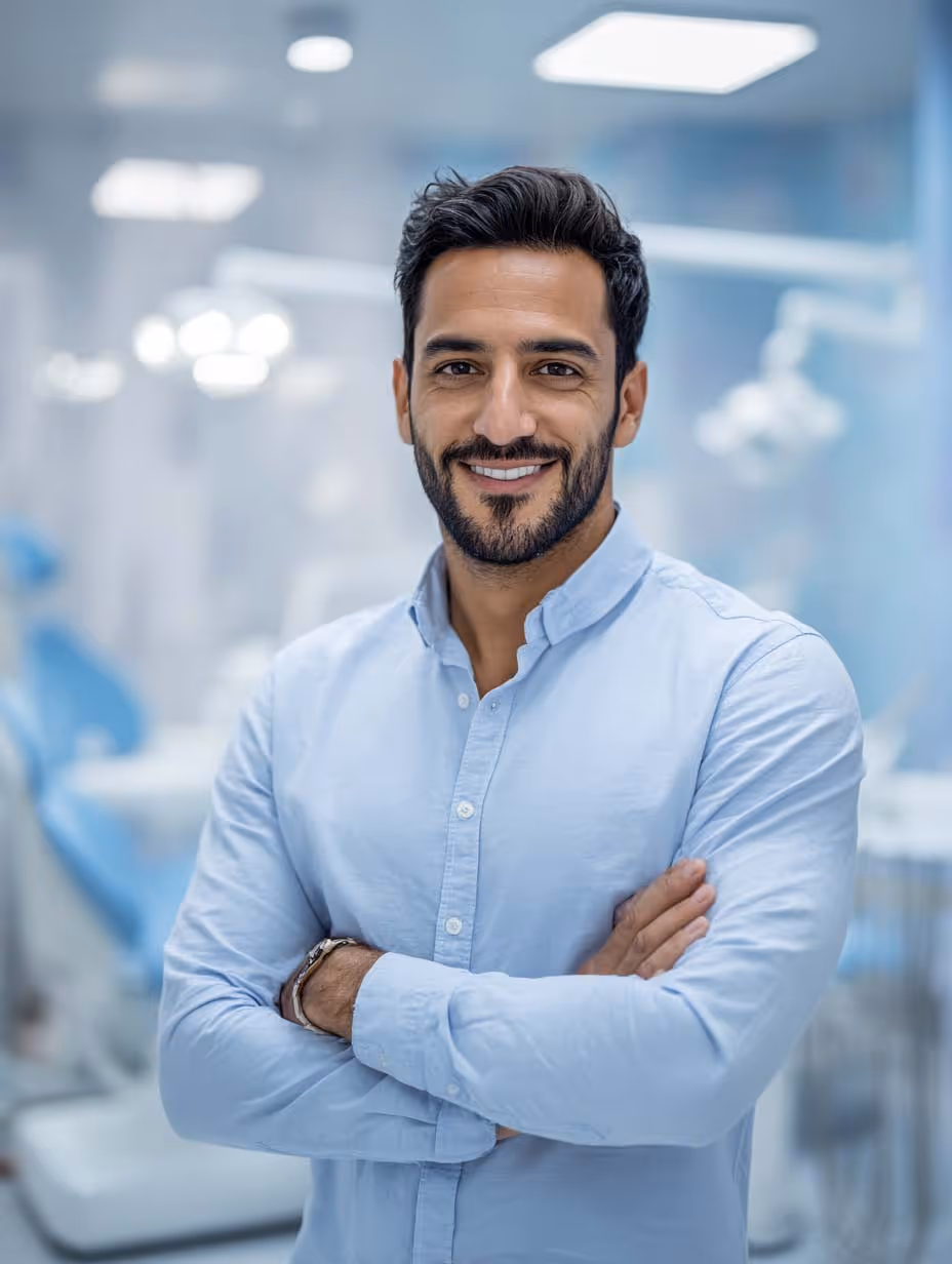 Homme souriant bras croisés dans un cabinet dentaire moderne et lumineux.
