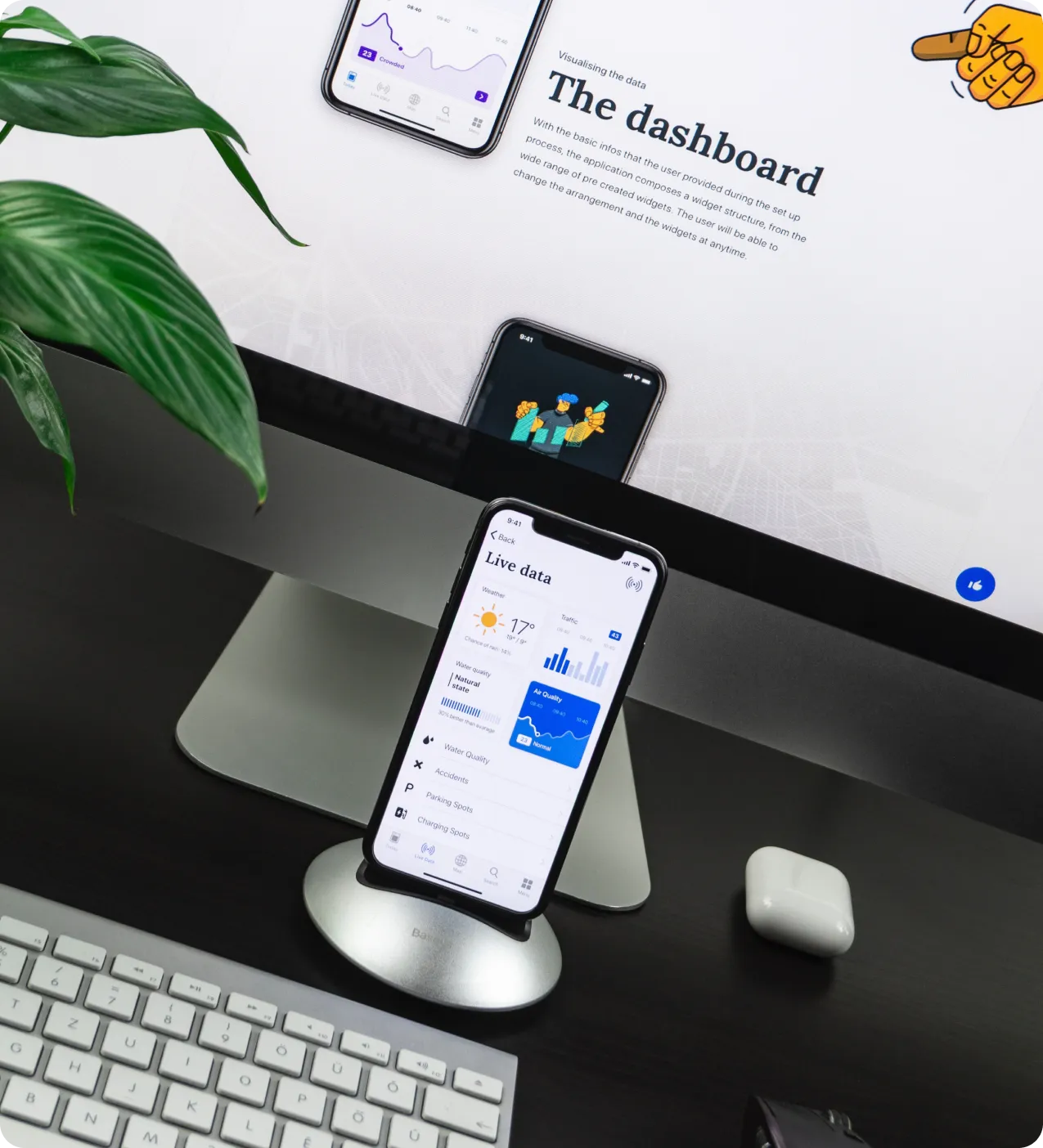 On desk we see iphone in dock station, iMac and magic keybord