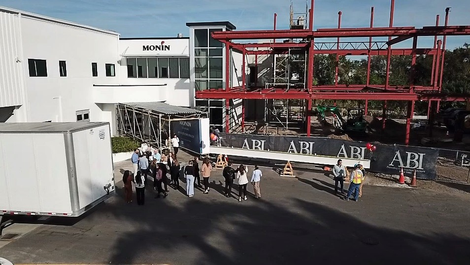 Groundbreaking ceremony at a construction site with people gathered and machinery present.