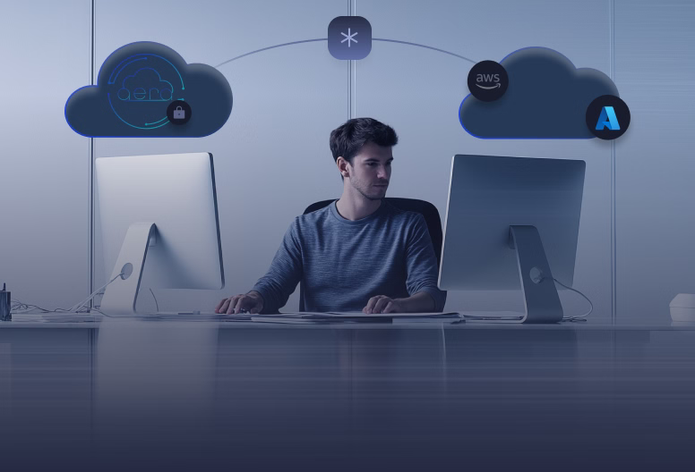 Man sitting at desk working on two desktop computers with cloud icons for hybrid cloud and AWS Azure connections above him.