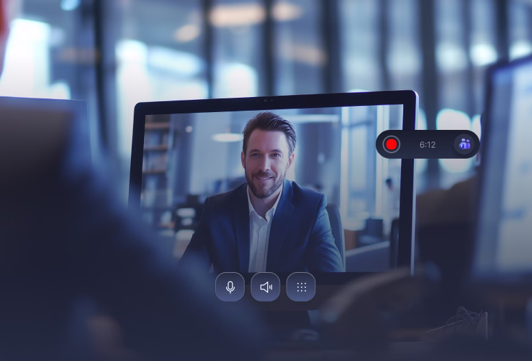 A man in a suit smiling during a video call on a computer screen with call controls visible.