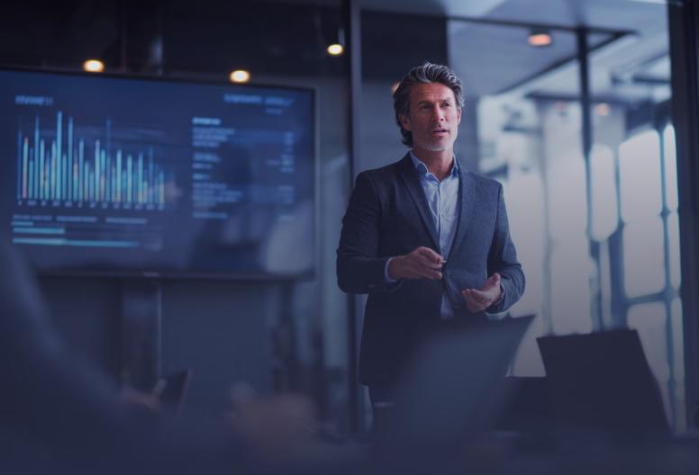 Businessman in a suit presenting data with a digital bar chart on a screen in a modern office.