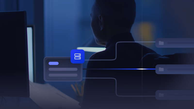 Silhouette of a person sitting at a desk with computer screens, overlaid with digital icons connected by lines representing data re-entry between systems.