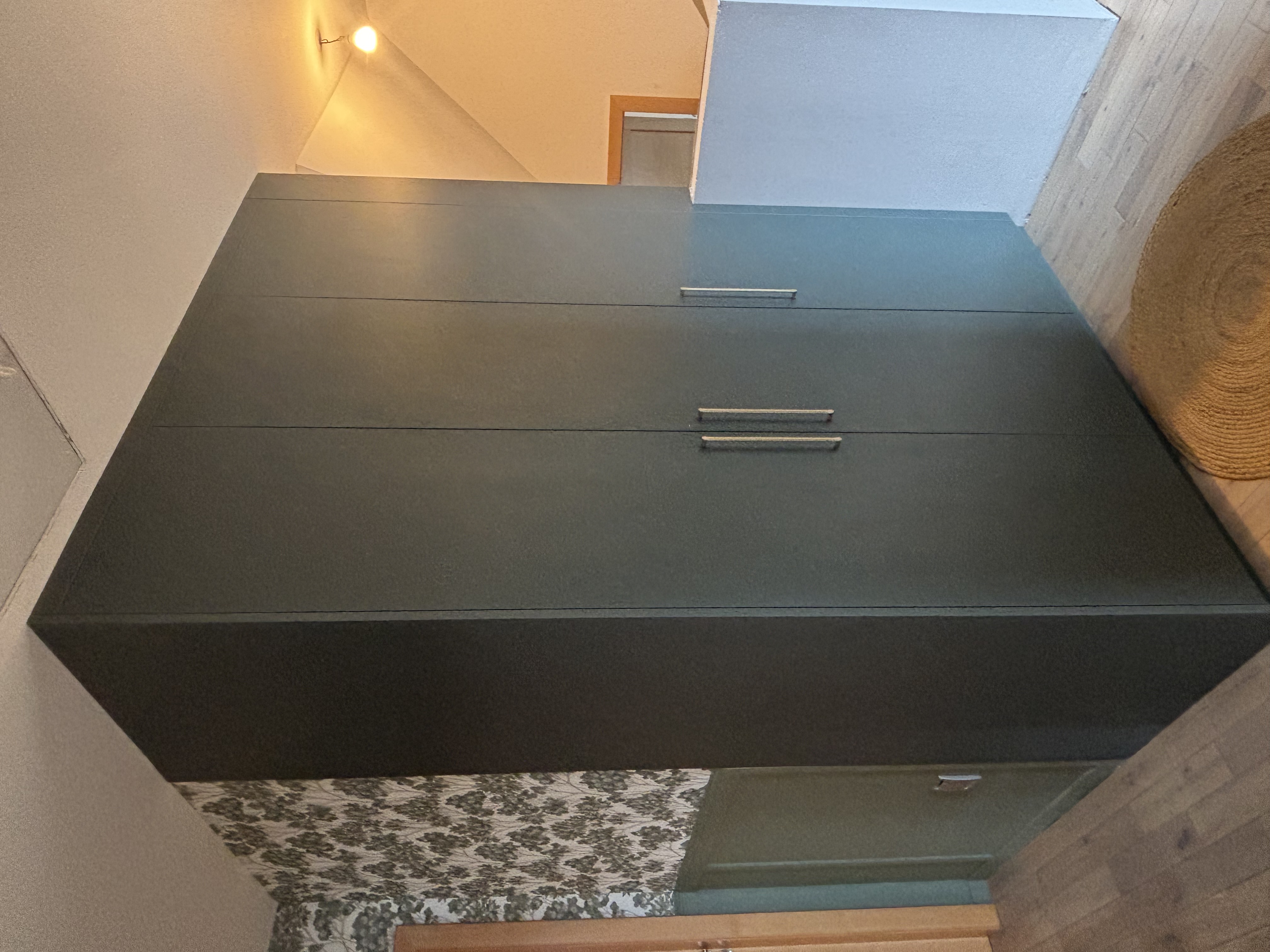 Ce meuble de rangement a été conçu sur mesure en tenant compte du retour du garde-corps, afin d’optimiser chaque centimètre disponible. Nous avons également intégré les poutres existantes dans la structure pour exploiter toute la profondeur et maximiser le rangement. Son coloris vert profond a été soigneusement choisi pour s’harmoniser avec l’ambiance décorative du lieu, apportant élégance et caractère à l’ensemble.