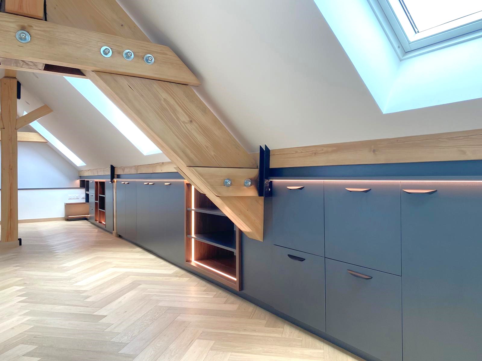 Transformés en un espace sur mesure, ces combles aménagés allient esthétisme et fonctionnalité. La lumière intégrée souligne chaque ligne, met en valeur les matériaux et révèle le charme des poutres apparentes, créant ainsi une atmosphère contemporaine, douce et raffinée.