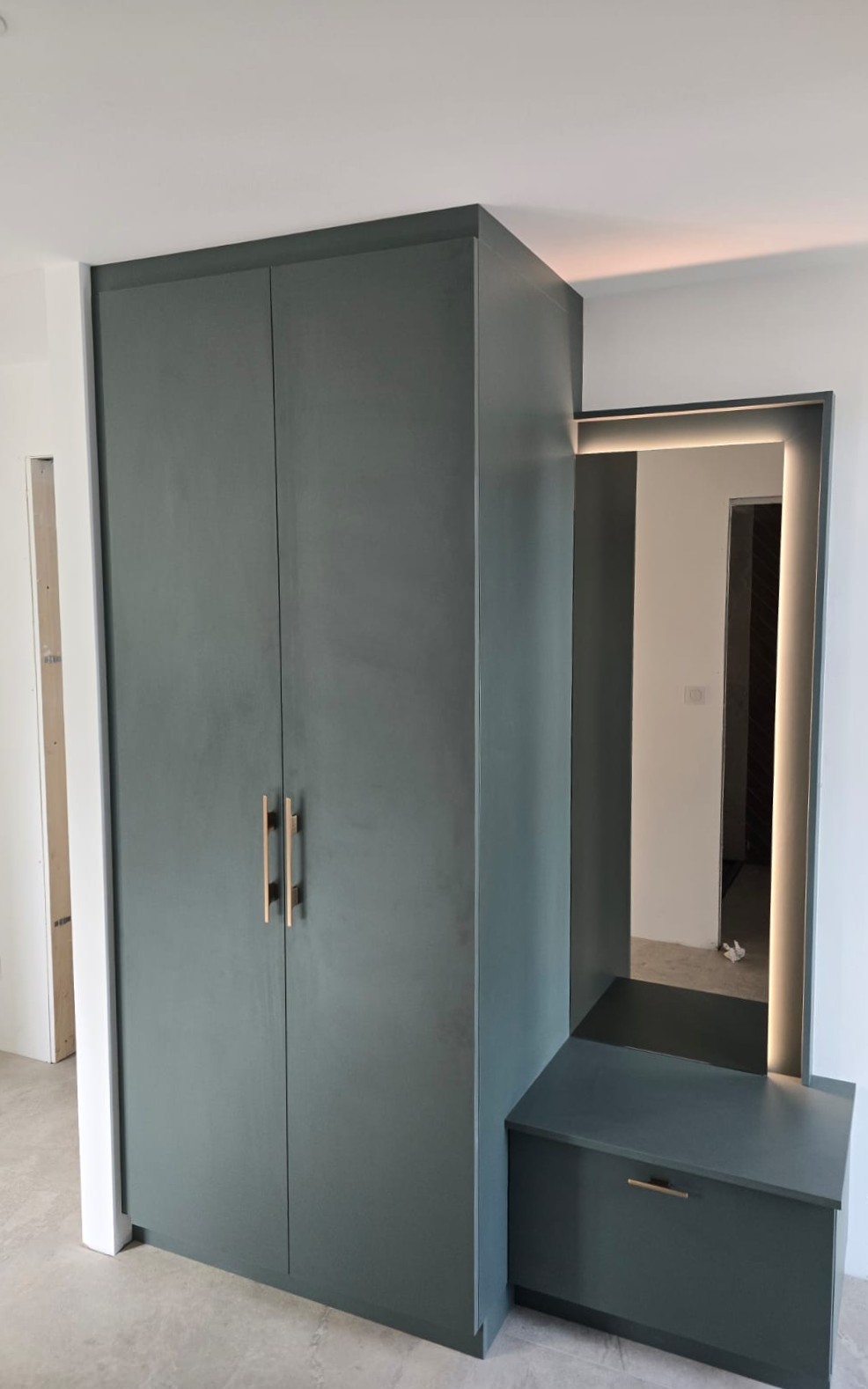 Un ensemble d'entrée qui combine design épuré et rangements astucieux. Des tirettes à chaussures intégrés, un banc d'assise et un grand miroir rétroéclairé pour la touche finale. 