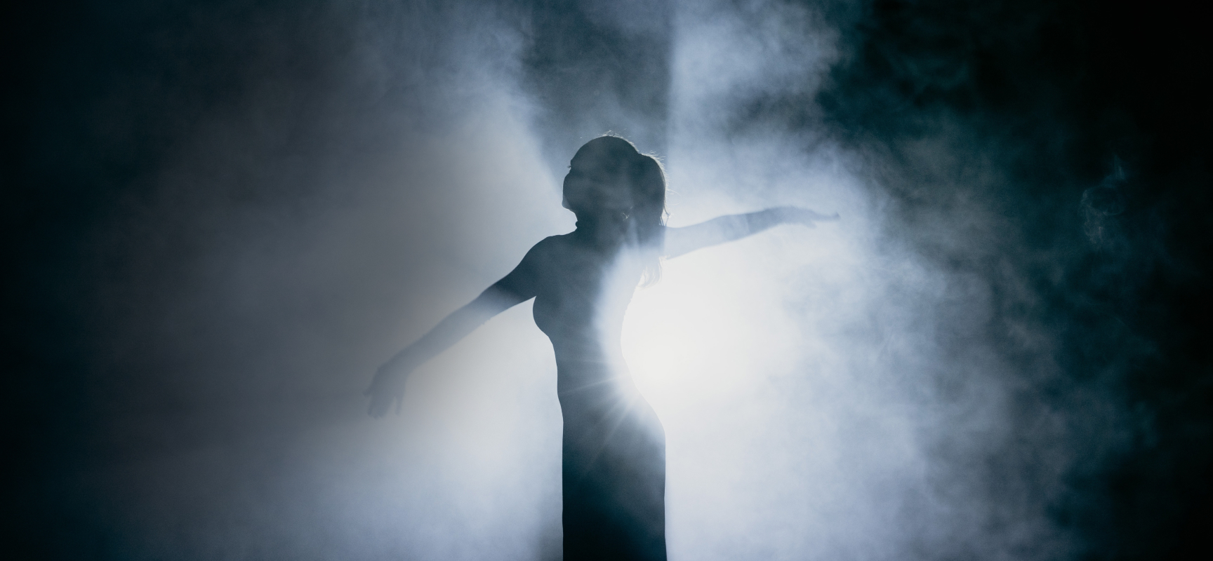 Actor on stage in smoke, with  a cloud of light billowing around her body