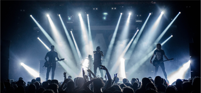 A rock gig with lights streaming at the act on stage.