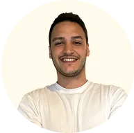 Smiling man with short dark hair wearing a white t-shirt, posed against a light background.