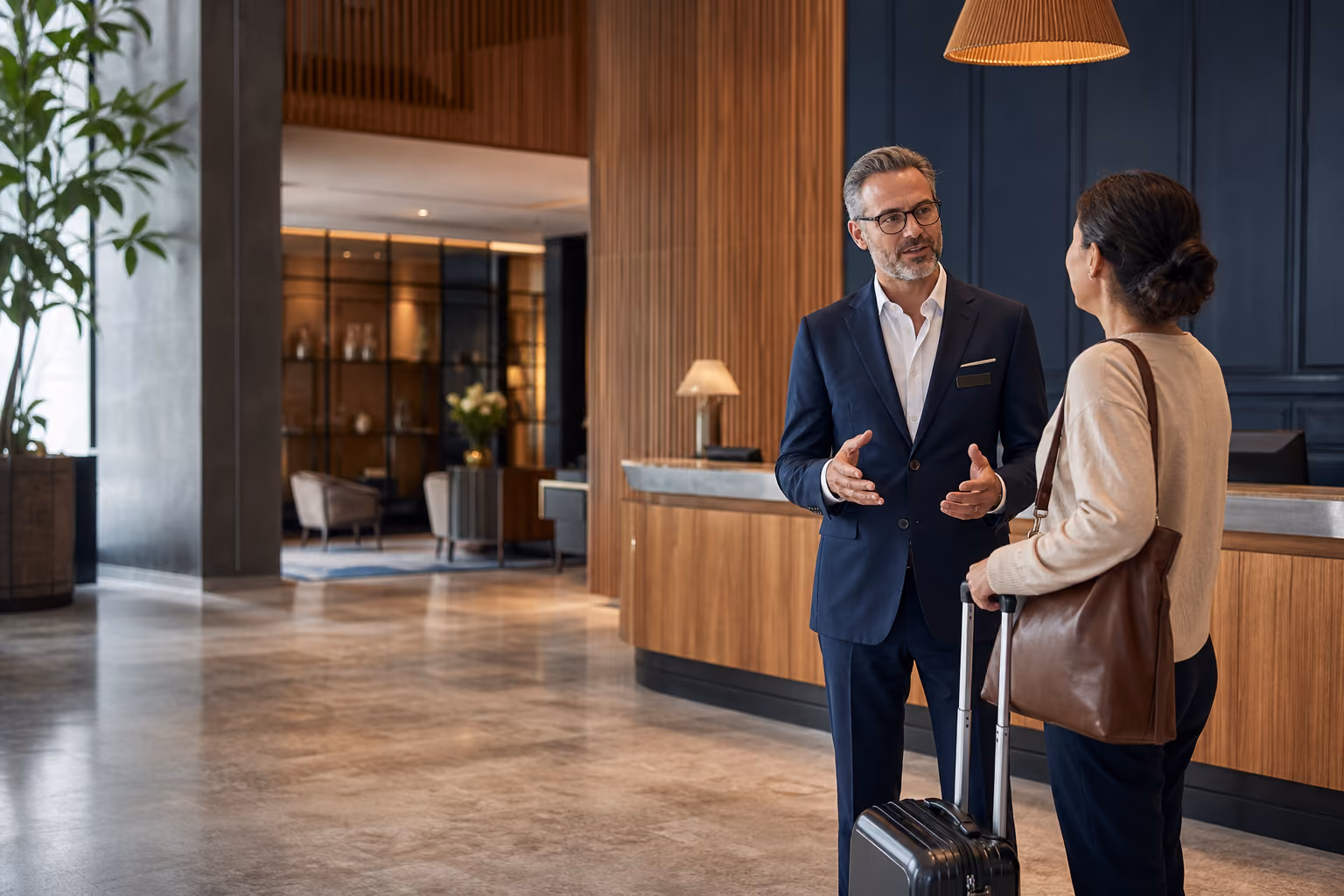 Hotel general manager speaking with a guest in a contemporary lobby