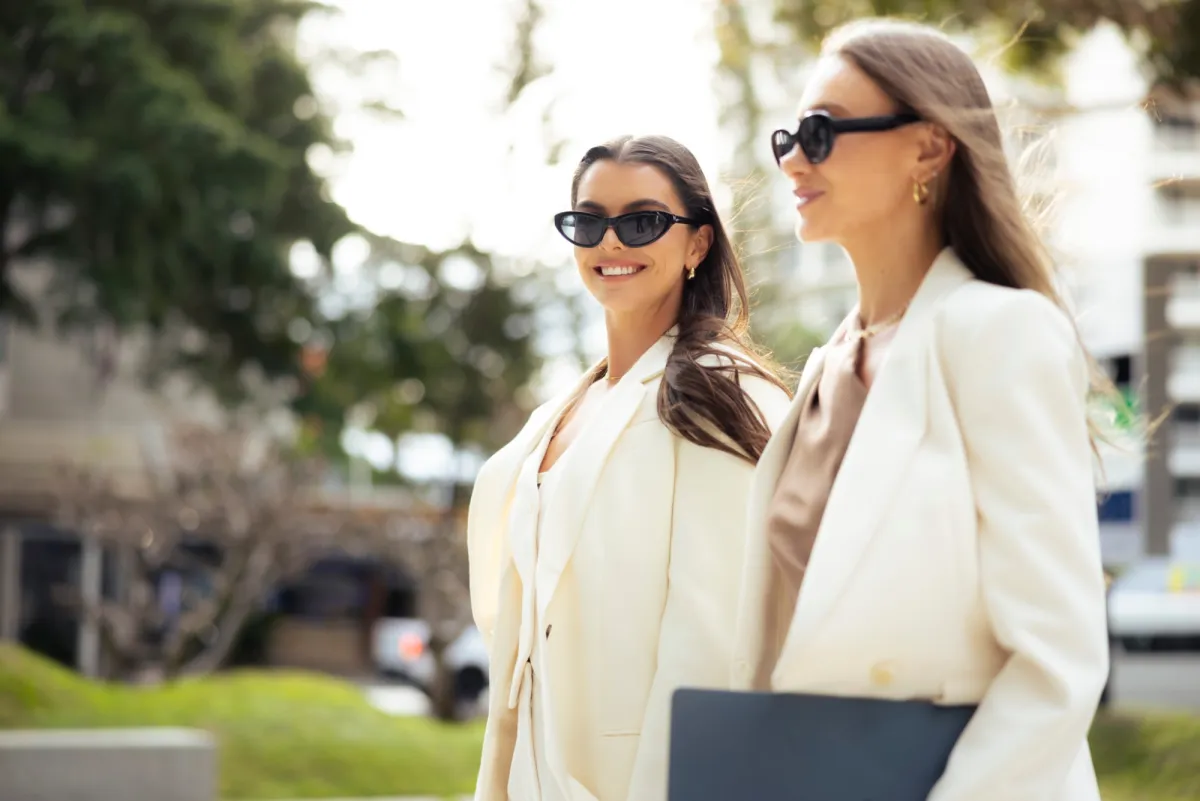 Two students in cream blazers walking outdoors