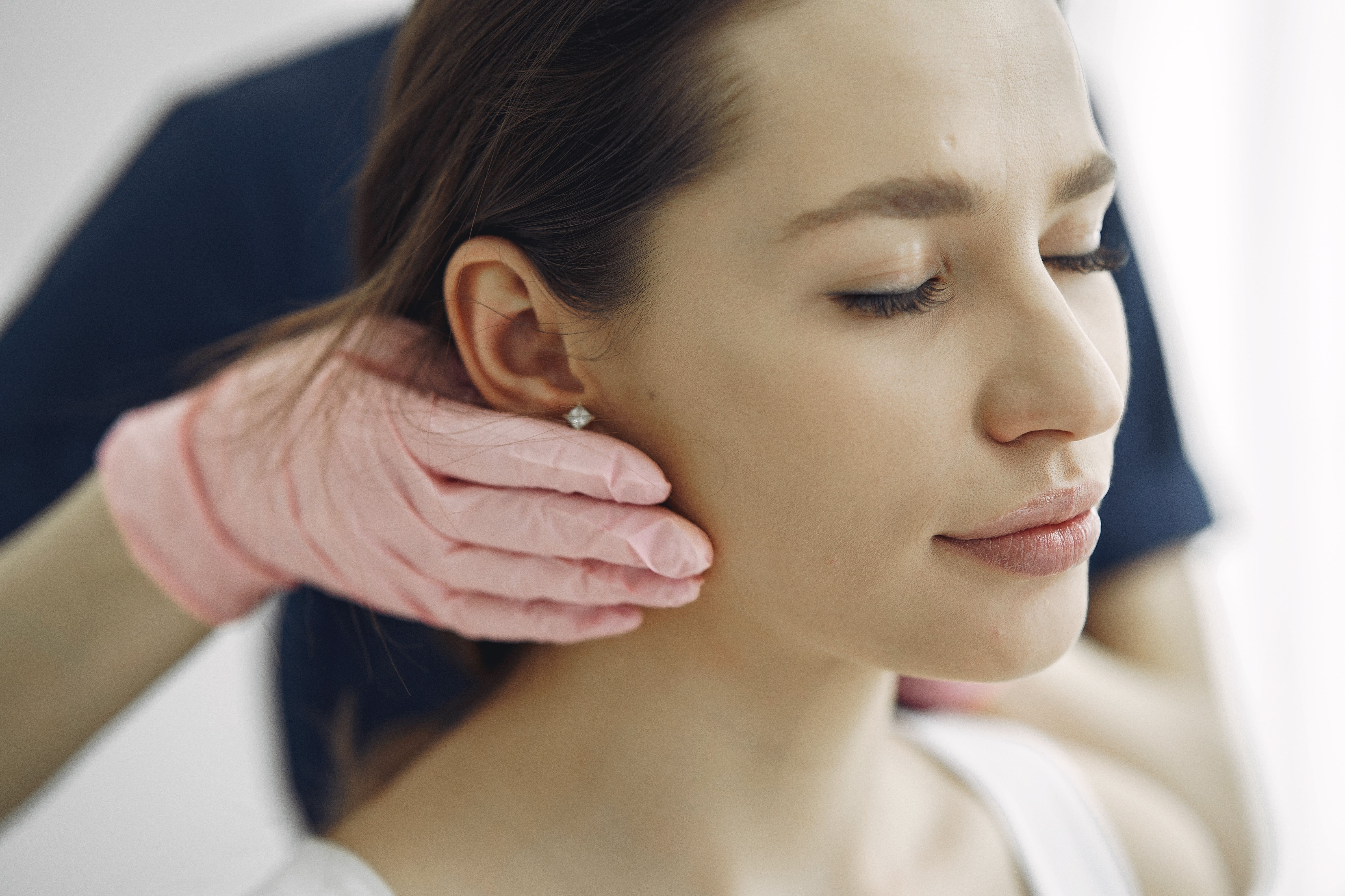 Dentist gently examining a patient's jaw and cheek during a consultation