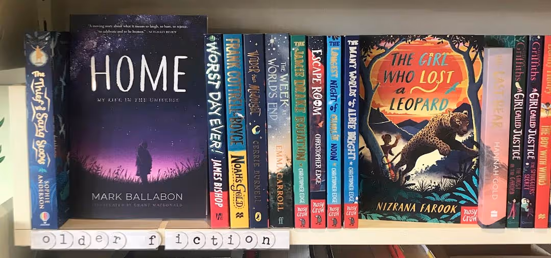 Book shelves inside a bookshop sowing fiction novels including "Home" by Mark Ballabon