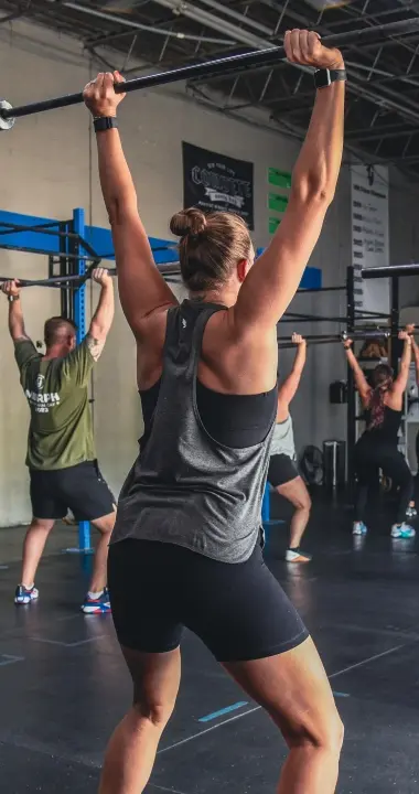 A group of members lifting barbells overhead during fitness classes at Graham Strength & Conditioning.